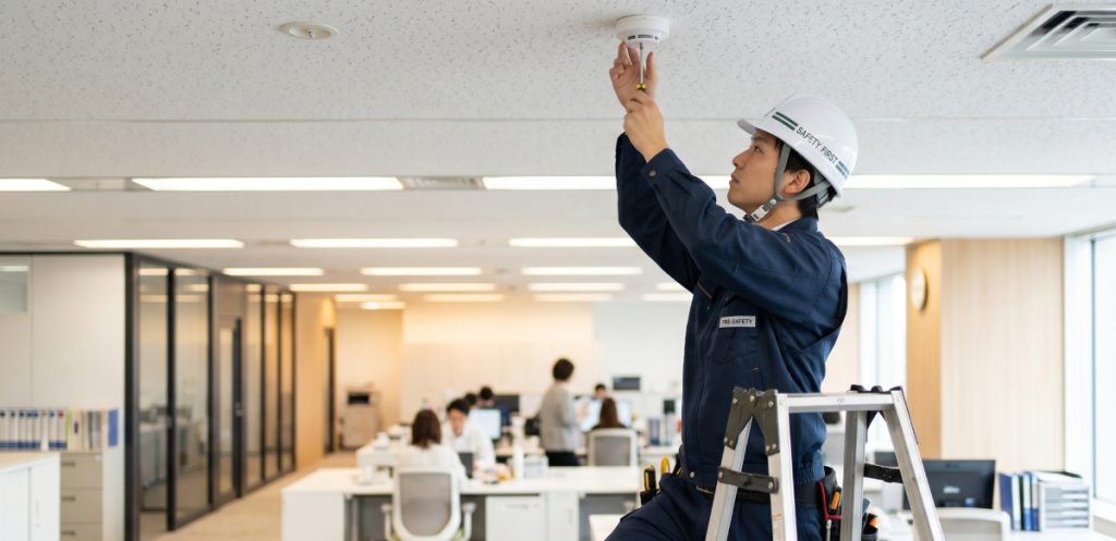 岡山市の消防設備士が天井に感知器を設置している消防設備工事作業の様子
